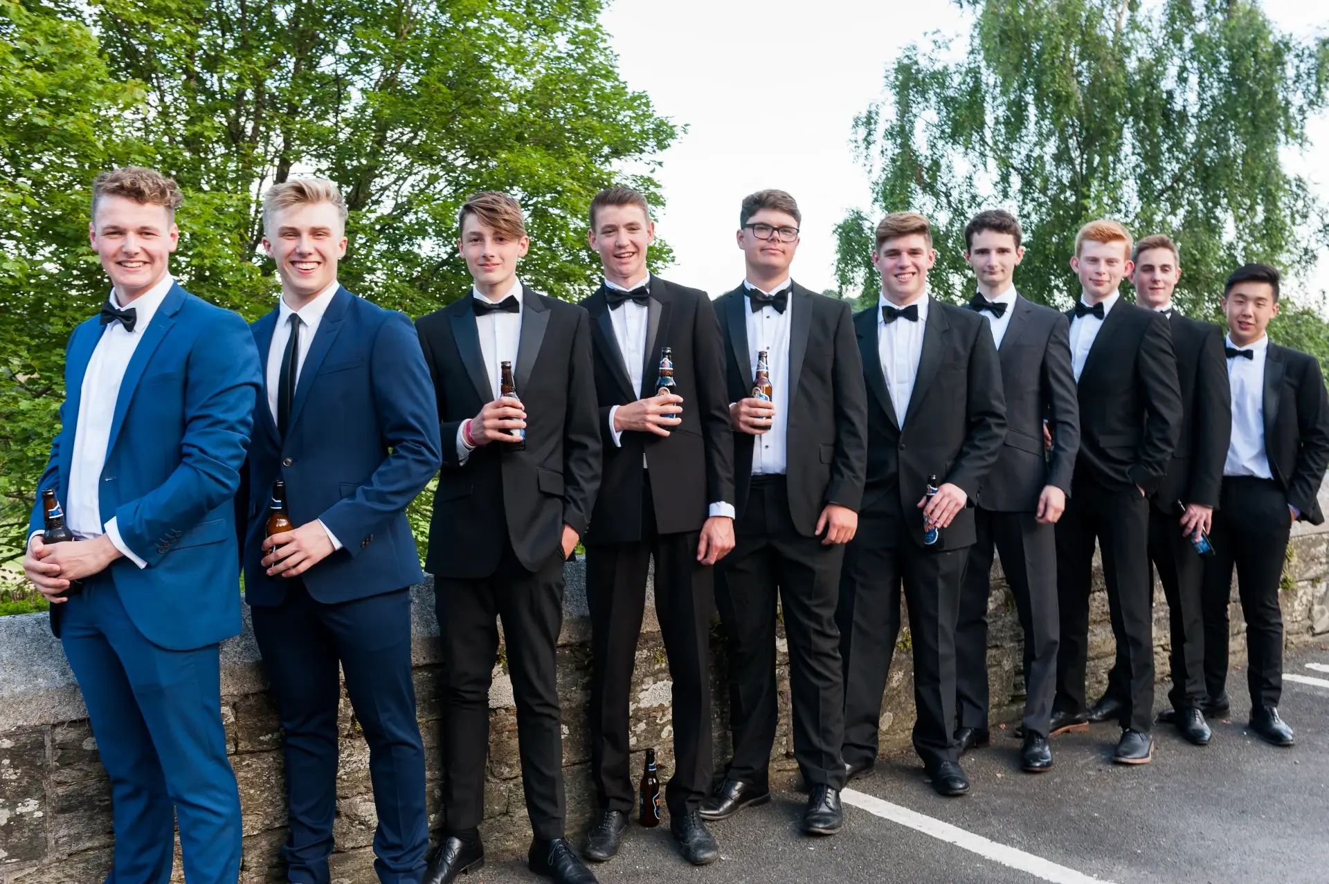 Formal group photo of groomsmen in suits at outdoor event