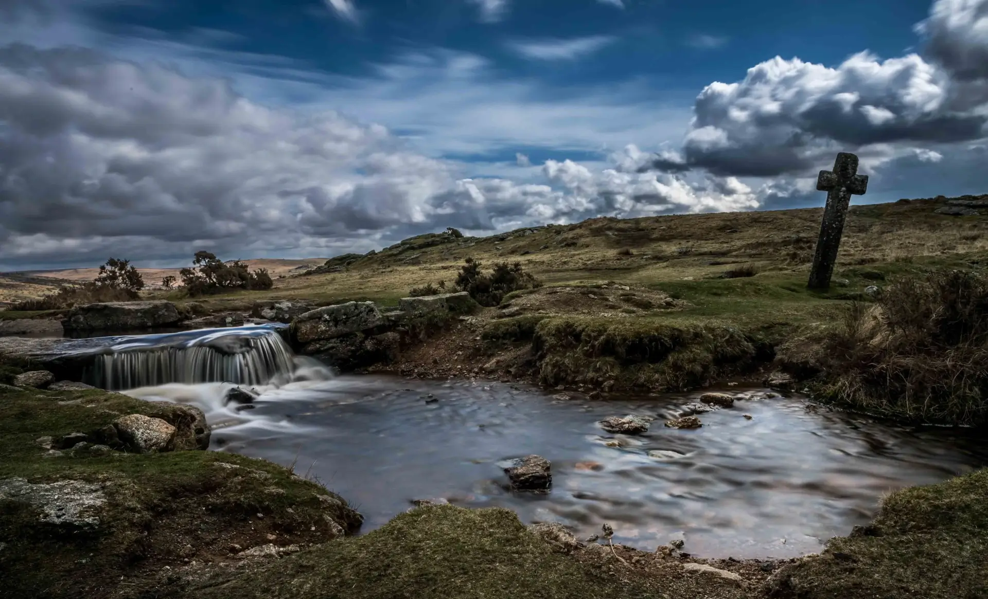 Moorland waterfall with ancient stone cross